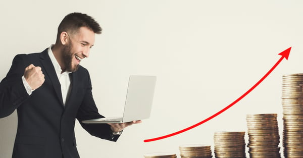 Happy man with a laptop facing increasing stacks of coins and a red arrow on an upward curve